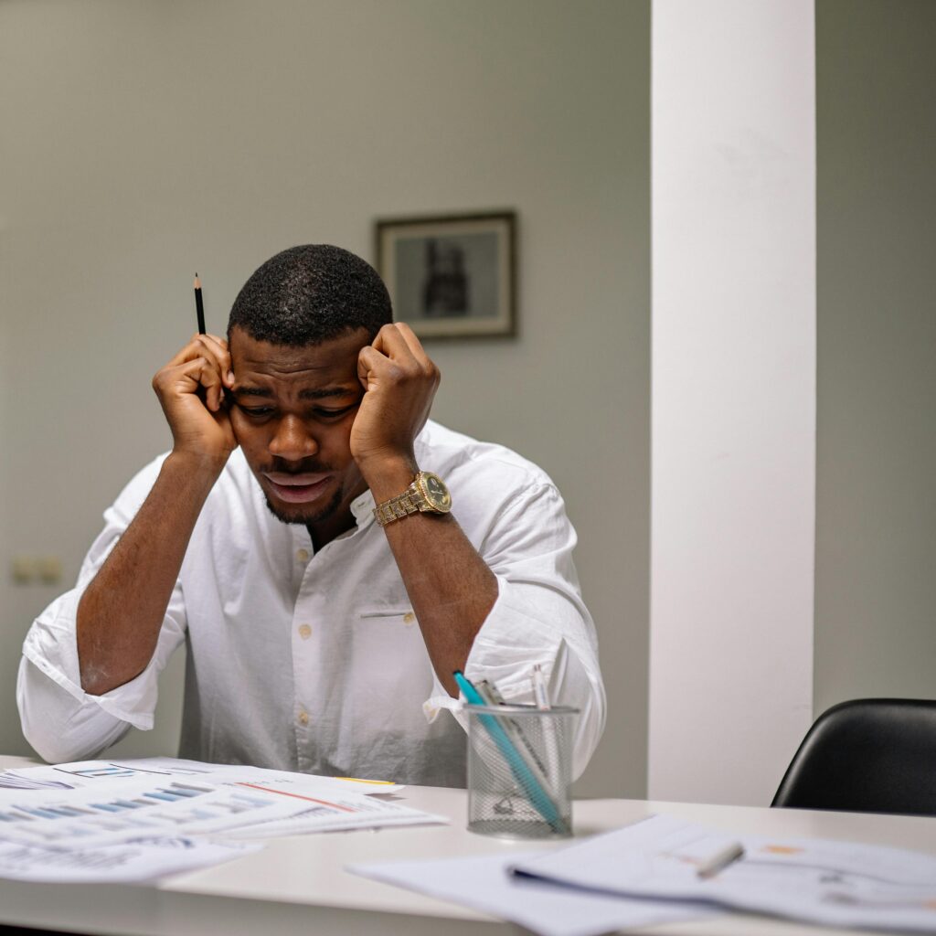 A worried businessman in corporate attire handling stress at his workspace.
